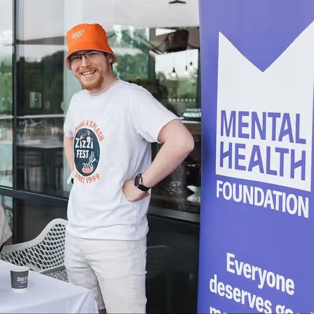 Staff member next to Mental Health Foundation donation flag