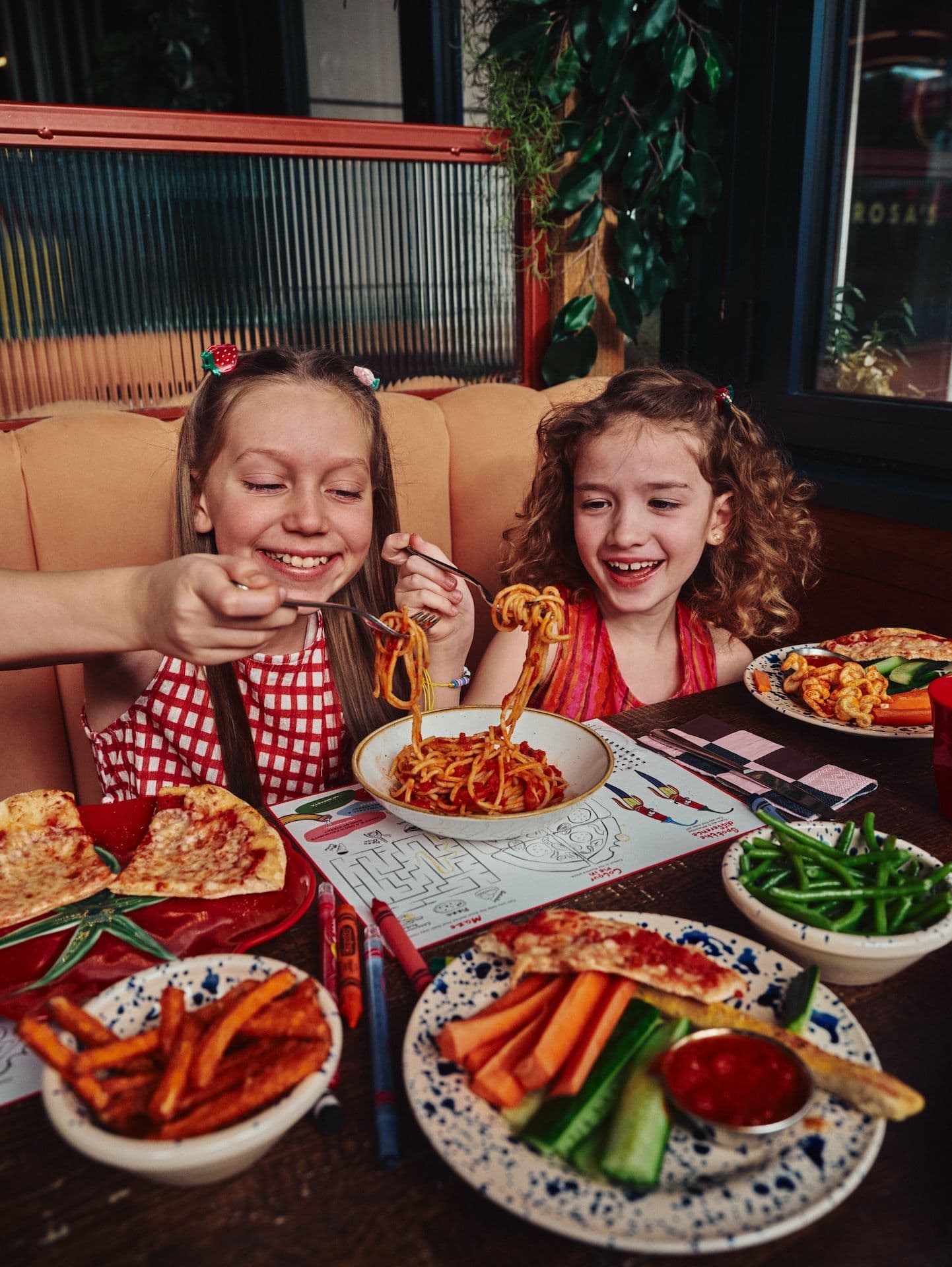 Kids eating pasta, veggies, pizza and chips